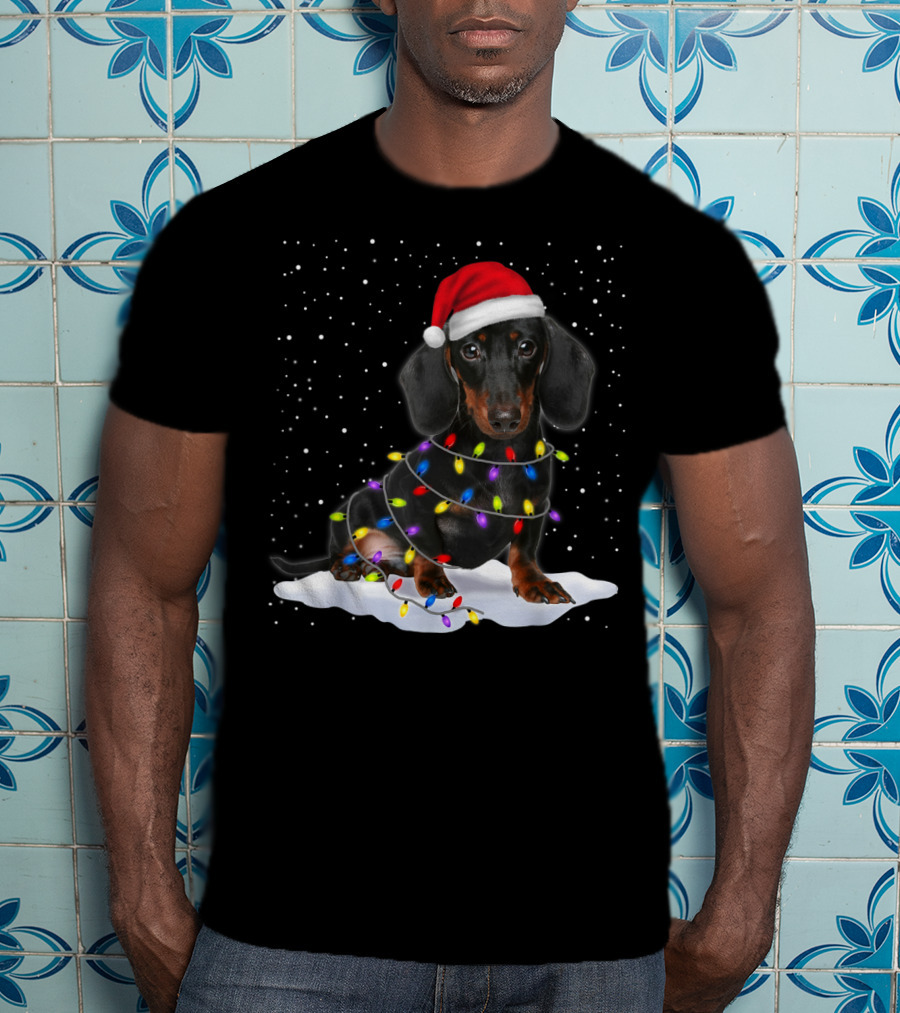 Dachshund Santa Hat Wrapped In Christmas Tree Lights In Snow With Falling Snowflakes T-Shirt