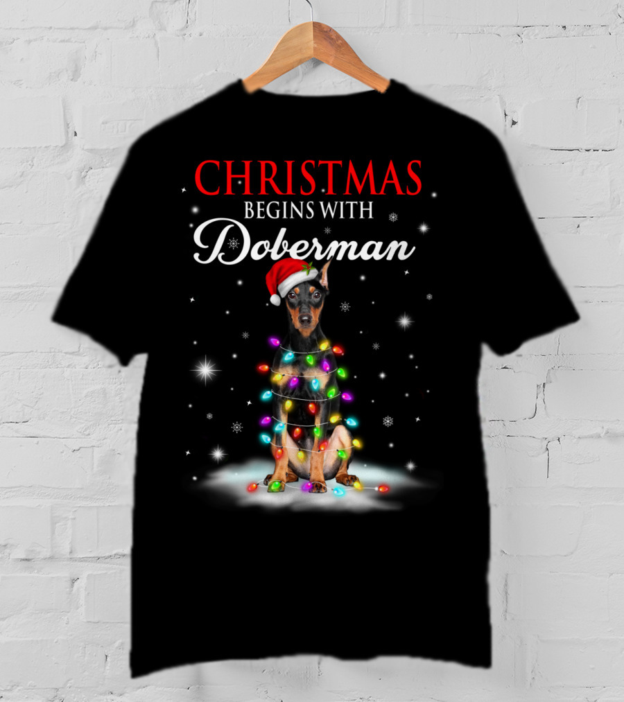 Christmas Begins With Doberman Wrapped In Holiday Lights And Santa Hat Snowflakes T-Shirt