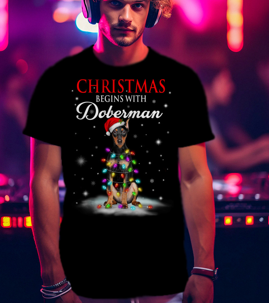 Christmas Begins With Doberman Wrapped In Holiday Lights And Santa Hat Snowflakes T-Shirt