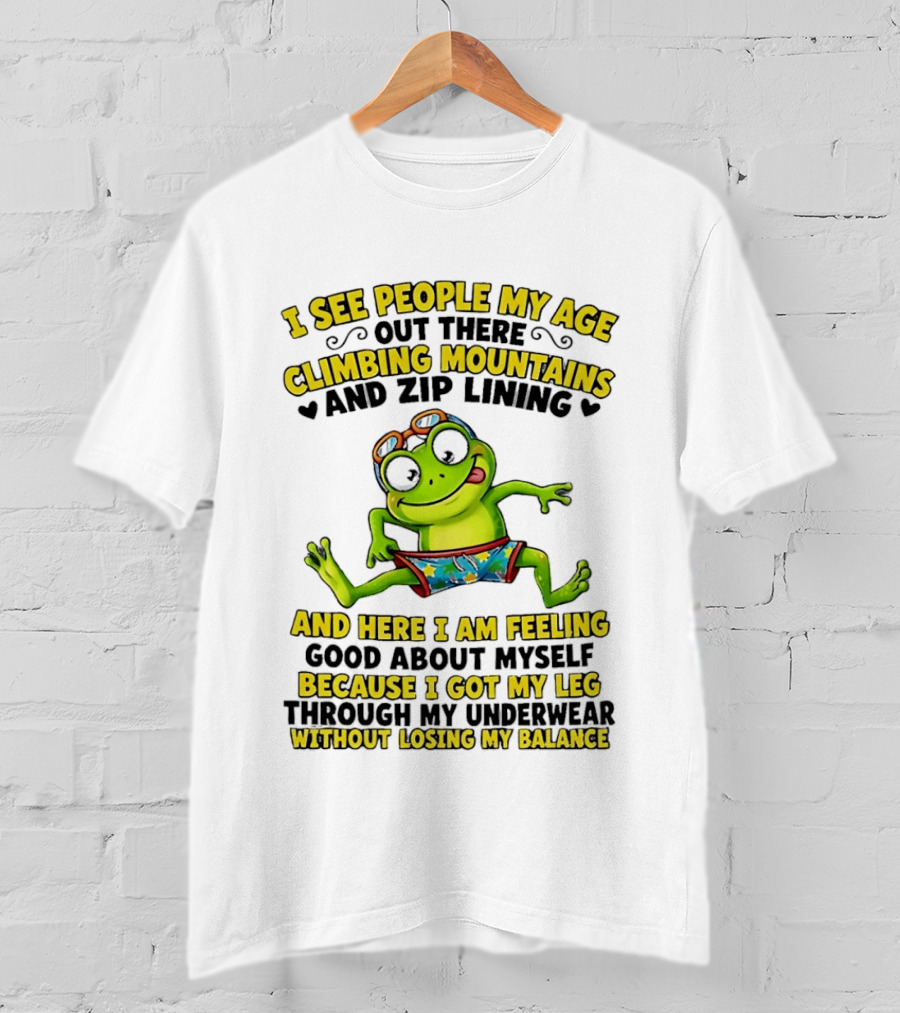 I See People My Age Climbing Mountains And Zip Lining Cartoon Frog Feeling Good Without Losing Balance T-Shirt