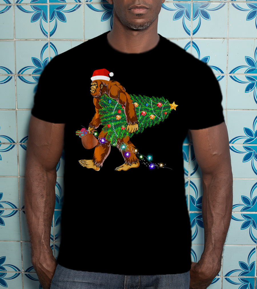 Santa Hat Bigfoot Holding Christmas Tree With Lights And Gifts T-Shirt